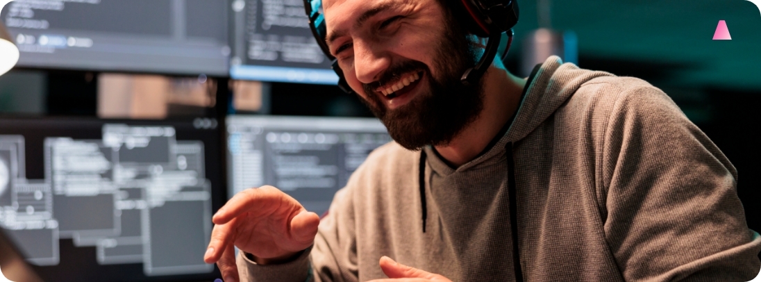Man laughing with headphones on in front of a monitor